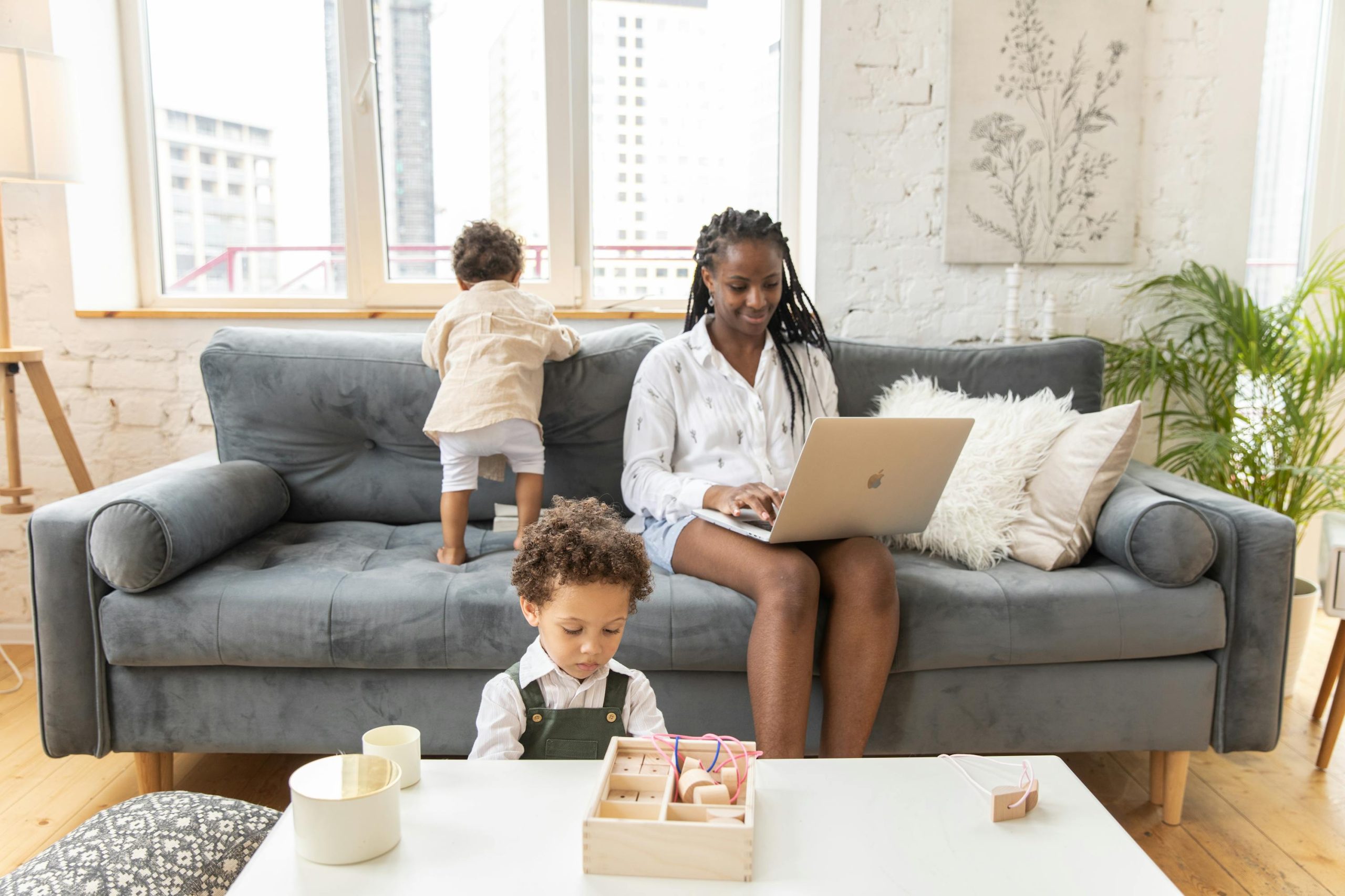 Working mom with two children sitting on a couch with her laptop