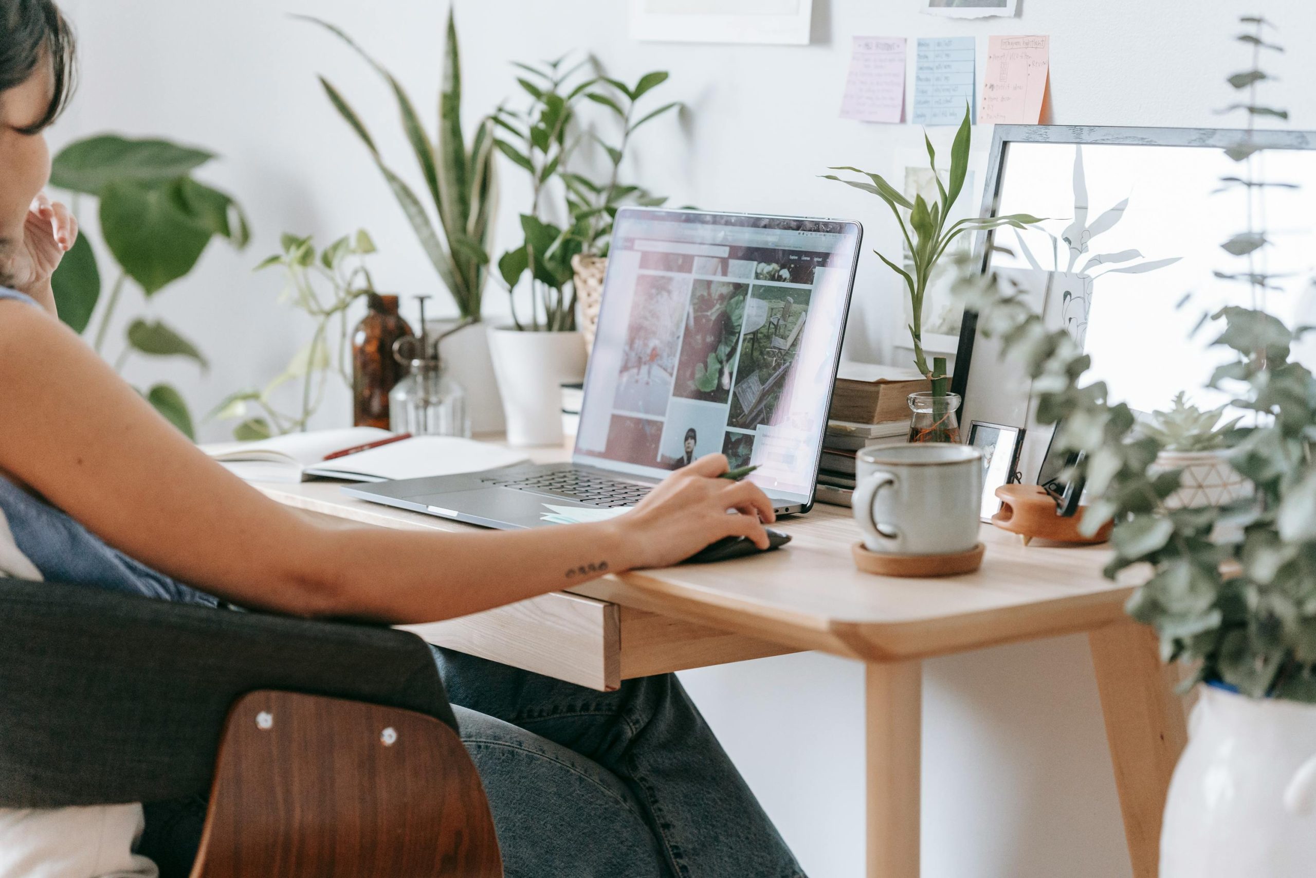 pexels-teona-swift-6913727 Woman sitting at laptop with coffee mug in a bright room with lots of house plants